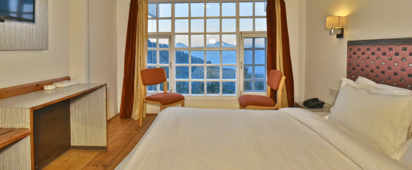 bedroom with large windows, showcasing natural light through open curtains at DLS Hillcrest Resort, Shimla